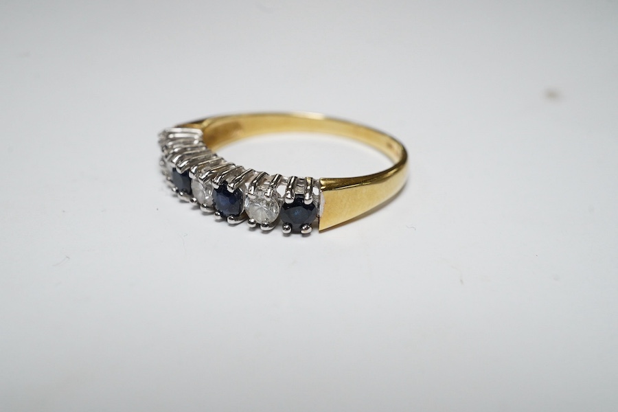 A modern 18ct gold, four stone sapphire and three stone diamond set half hoop ring, size L/M, gross weight 2.4 grams. Condition - fair to good